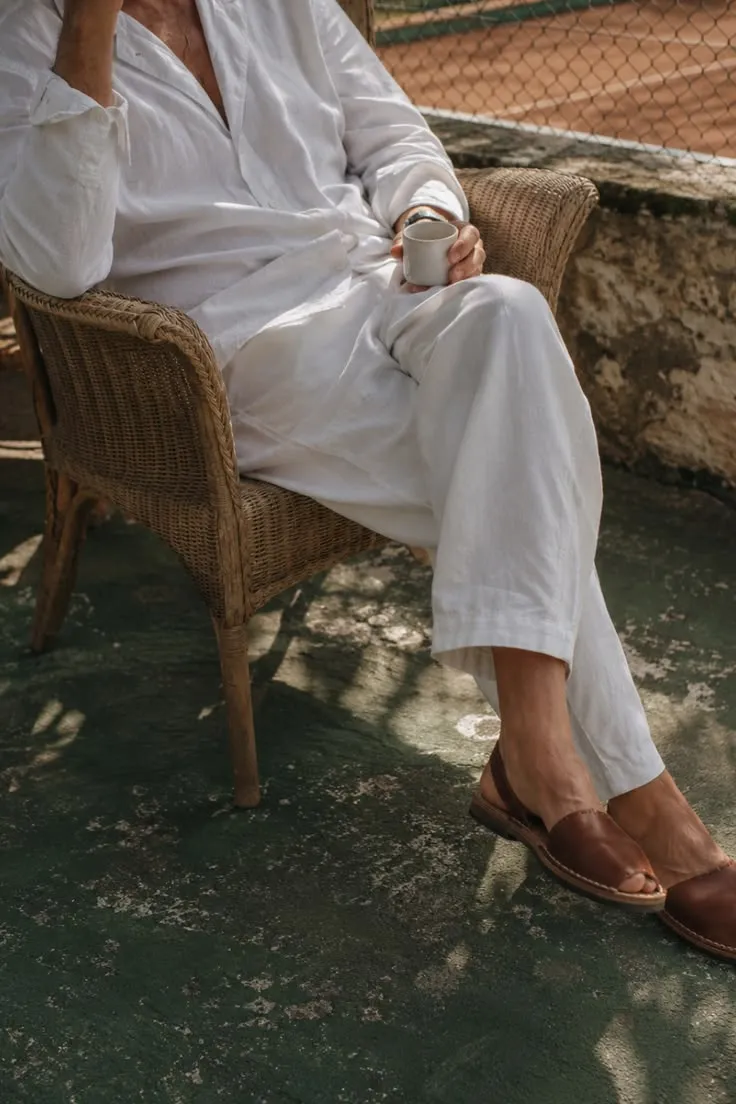 A guest in white linen resting in a shaded courtyard